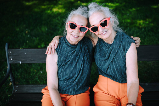 High angle view of happy senior women, twins in same clothes, smiling and posing in a city park. - Foto, immagini