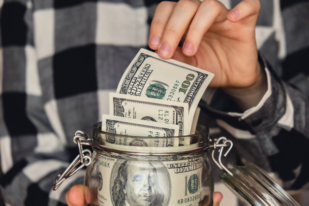 Dollar banknote saving money in glass jar. Unrecognizable woman moderate consumption and economy Collecting money. Tips. Business, finance, saving, banking and people concept. Extra money, passive - Foto, Imagem
