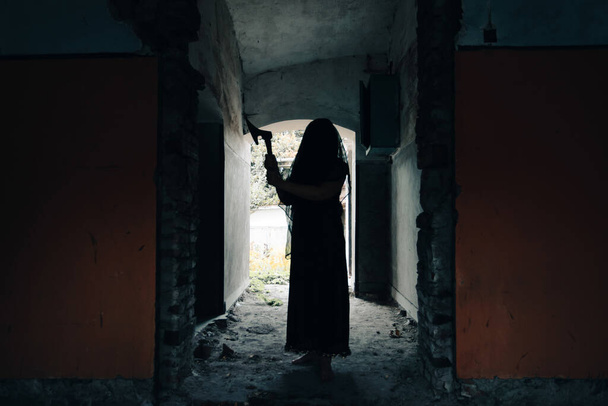 Ghost in abandoned, haunted house. Horror scene of spooky silhouette holding old axe, halloween concept. - Valokuva, kuva