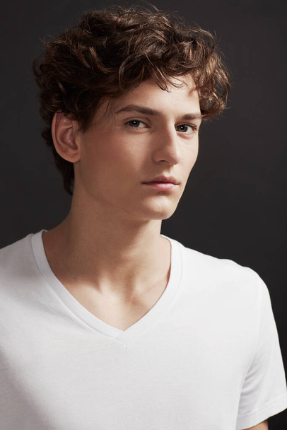 Clean-cut and fresh-faced. A handsome young man with elegant facial features glancing at you - Valokuva, kuva