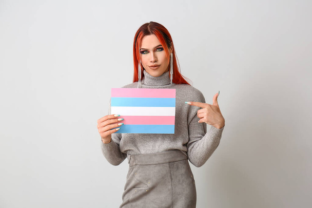 スタイリッシュなトランスジェンダーの女性は、ライトバックにトランスジェンダーのフラグを保持 - 写真・画像