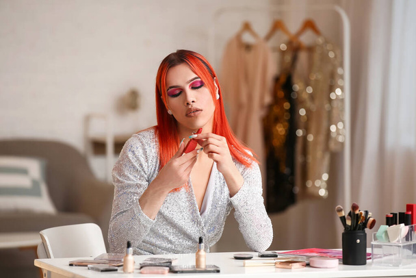 Young transgender woman doing makeup at home - 写真・画像