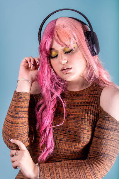Non-binary woman listening to music with wireless headphones. - Zdjęcie, obraz