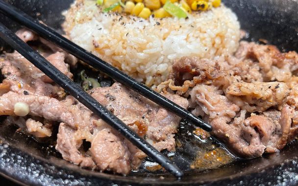 επιλεκτική εστίαση ψητό μοσχάρι μπριζόλα με κορεάτικη σάλτσα bulgogi πάνω από το ρύζι με φέτα πιπέρι και γλυκό καλαμπόκι - κορεάτικο και ιαπωνικό στυλ τροφίμων σε ένα εστιατόριο - Φωτογραφία, εικόνα