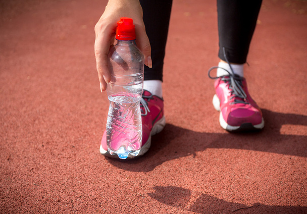 donna corridore in possesso di bottiglia di plastica di acqua sulla pista di corsa
 - Foto, immagini