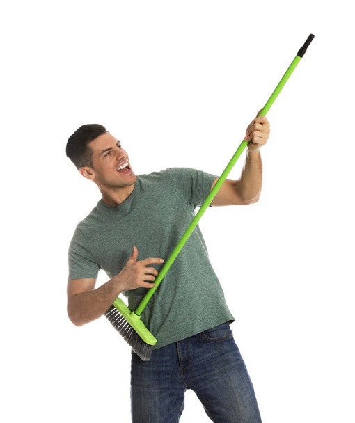 Man with green broom having fun on white background - Foto, Imagen