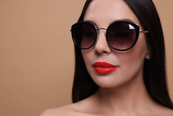 Attractive woman in fashionable sunglasses against beige background, closeup. Space for text - Fotó, kép