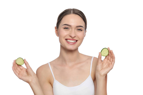 Young woman with cucumber slices on white background. Eye skin care - 写真・画像