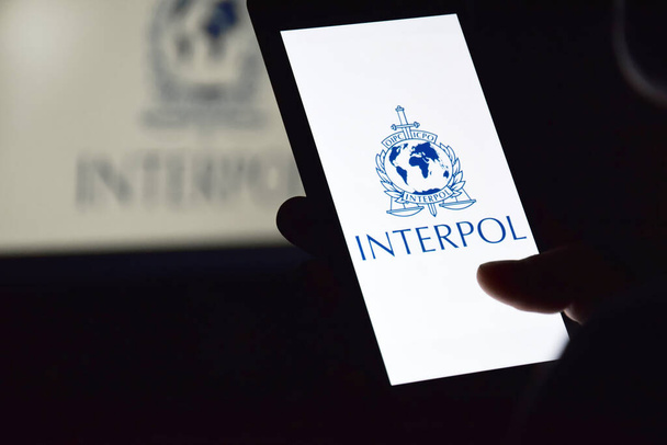 Kharkiv, Ukraine - 16 juin 2022 : Personne tenant un smartphone avec le logo Interpol affiché à l'écran. Organisation internationale de police criminelle ou Interpol. - Photo, image