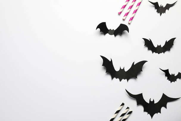 Flat lay composition with paper bats and straws on white background, space for text. Halloween celebration - Photo, image