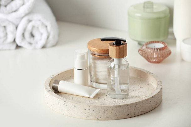 Vassoio con flacone dosatore e prodotti cosmetici su tavolo bianco in bagno - Foto, immagini