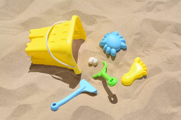 Bright plastic bucket, rake and shovel on sand. Beach toys - Foto, Bild