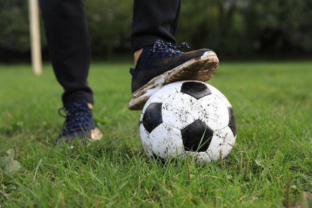 Man with dirty soccer ball on green grass outdoors, closeup - Foto, Bild