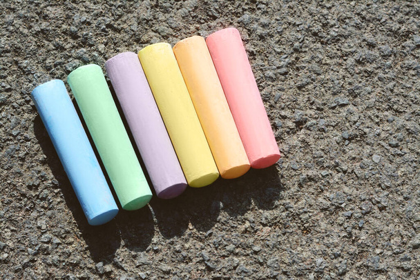 Colorful chalk sticks on asphalt, flat lay. Space for text - Foto, imagen