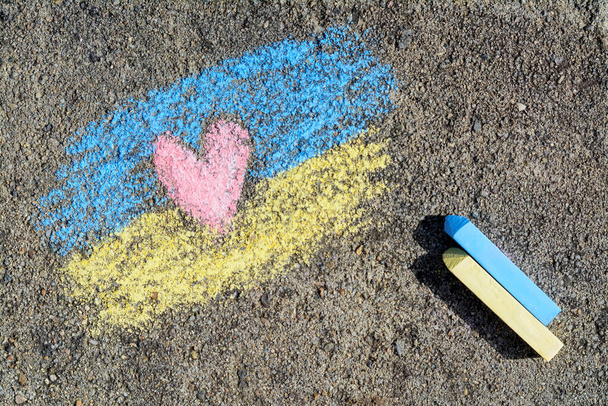 National flag of Ukraine with heart drawn by color chalk and sticks on asphalt, flat lay - Photo, image