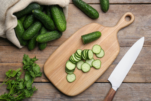 Fresh ripe cucumbers and parsley on wooden table, flat lay - 写真・画像