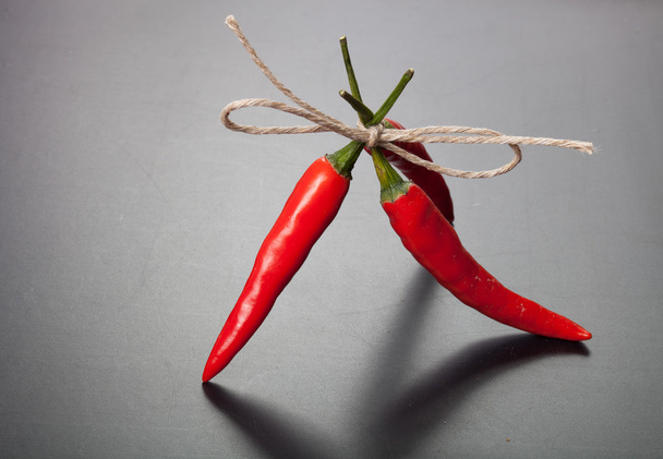 red hot chili peppers tied twine against dark background - Foto, Imagen