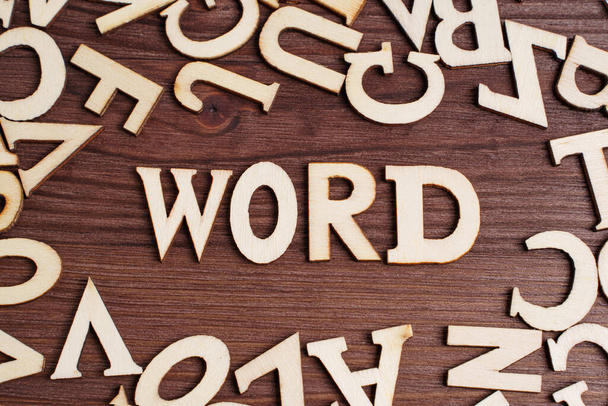 Wooden letters arranged into a WORD text on a dark wooden table. Creative study concept. - Фото, зображення