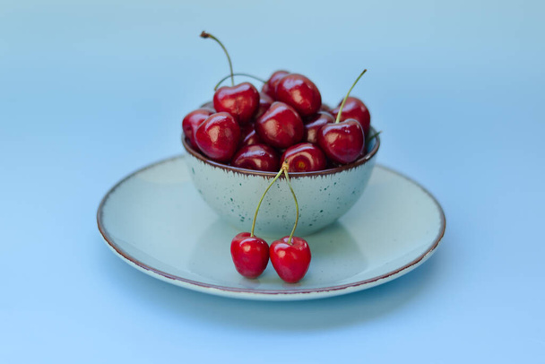 Top view of red sweet cherry on blue plate close up. Vegan, summer food concept. Diet - Photo, Image