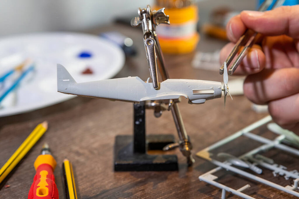Kriegsflugzeug Modellbau oder -bau, Handarbeit auf Tisch mit verschiedenen Materialien. - Foto, Bild