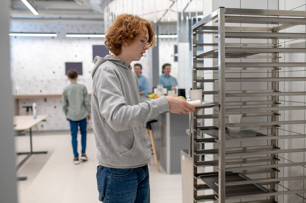At the school canteen. School boy putting his tray to the kitchen shelves after lunch - Valokuva, kuva