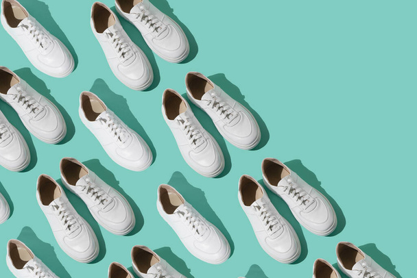 White sneakers pattern on a mint blue background. The shoes are comfortable and casual. Background for a shoe store. A pair of new sneaker shoes. - 写真・画像
