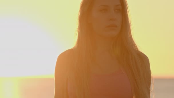Beautiful woman against a sparkling sea and sky at sunrise - Záběry, video