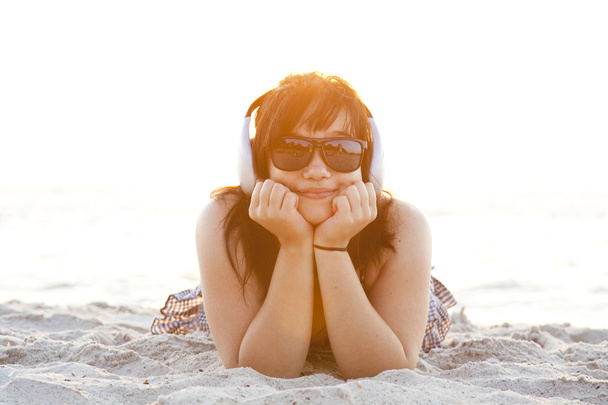 Beautiful brunette girl with headphones at beach sand. - Fotó, kép