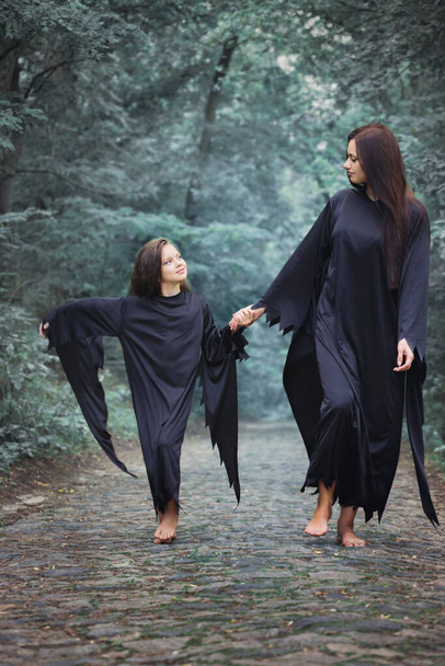 An adult witch and her daughter are walking in the forest, Halloween concept - Fotó, kép