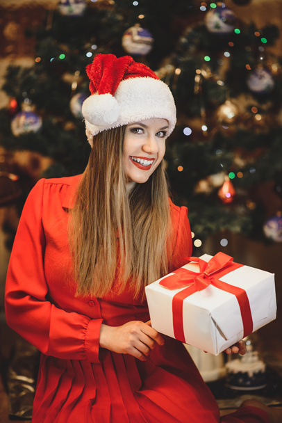 Beautiful girl in a Christmas hat with a gift - Zdjęcie, obraz