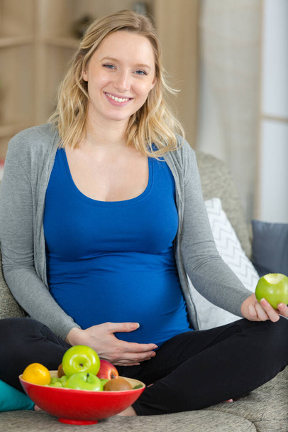 happy pregnant woman eating an apple - 写真・画像