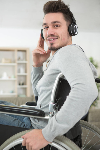 young handsome man in wheelchair listening to music - Zdjęcie, obraz
