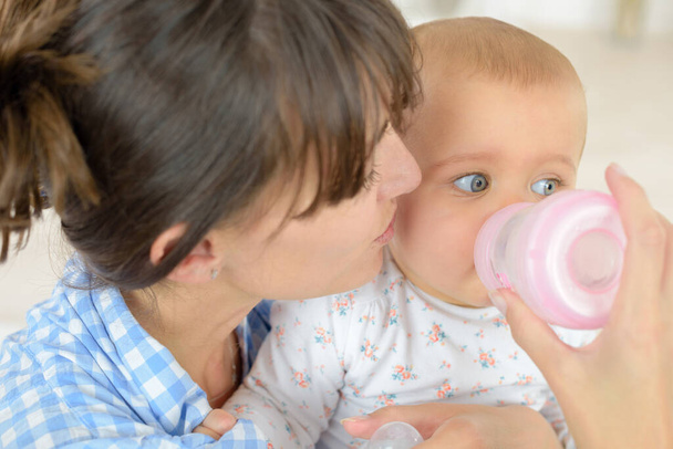 mother feeding baby boy with a milk bottle at home - Photo, Image