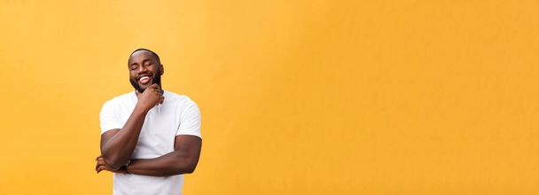 Portret van een moderne jonge zwarte man die lacht met armen gekruist op geïsoleerde gele achtergrond. - Foto, afbeelding