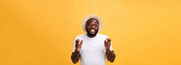Jonge Afro-Amerikaanse man over geïsoleerde achtergrond glimlachend kruising vingers met de ogen gesloten en hoop. Geluk en bijgelovig concept. - Foto, afbeelding