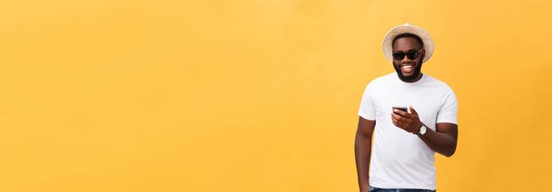 Vrolijke African American man in een wit overhemd met behulp van de mobiele telefoon applicatie. Gelukkig donkere gevilde hipster man Lees nieuws van sociaal netwerk in mobiele telefoon - Foto, afbeelding
