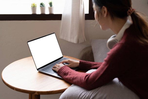 Houkutteleva hymyilevä nuori nainen käyttää kannettavaa tietokonetta sohvalla kotona. elämäntapa käsite. - Valokuva, kuva