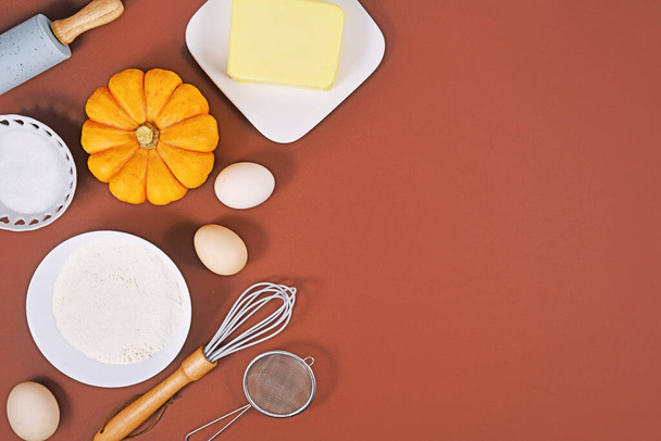 Ingredients and baking tools for pumpkin pie on brown background with copy space - Φωτογραφία, εικόνα