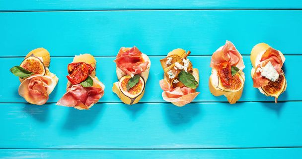 Appetizers board with traditional spanish tapas set. Italian antipasti bruschetta with prosciutto, cream cheese and fig. top view. - Photo, Image