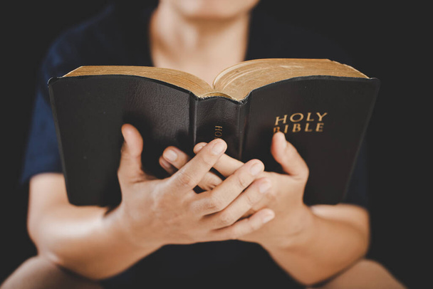 家庭で勉強して聖書を持っている若い女性の手。成人女性クリスチャンは教会で本を読んでいます。女の子は神への祈りで宗教精神性を学ぶ。学生教育の理念. - 写真・画像