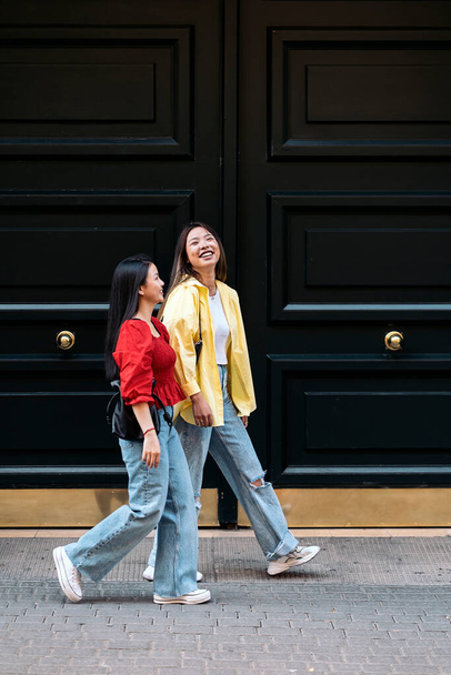 Trendy asian female friends talking while walking in the city. - Фото, зображення