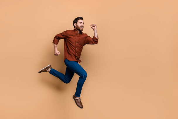 Full body profile portrait of sporty energetic person jump running empty space isolated on beige color background. - Photo, Image