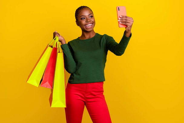 Photo of confident sweet woman wear green shirt holding shoppers tacking selfie modern device isolated yellow color background. - Foto, Imagen