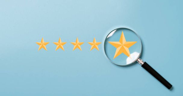 cinco estrellas doradas dentro de la lupa sobre fondo azul para centrarse en la excelente evaluación del cliente después del uso del producto y el concepto de servicio del cliente. - Foto, imagen