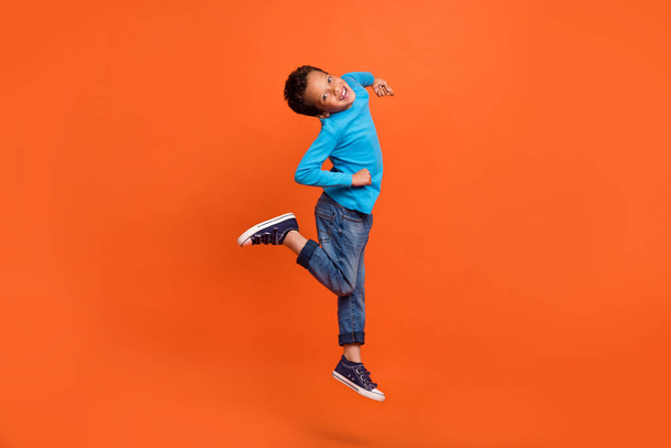 Ful body photo of cute small schoolboy jumping have fun playful fooling dressed stylish blue outfit isolated on orange color background. - Fotografie, Obrázek