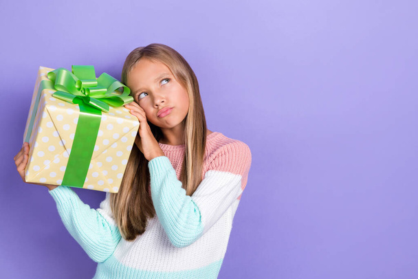 Photo of concentrated uncertain unsure girl hold birthday package look up empty space decide isolated on purple color background. - Φωτογραφία, εικόνα