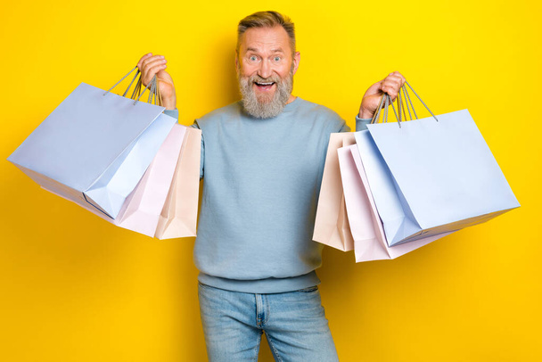 Portrait of positive aged man hands hold boutique packages isolated on yellow color background. - Valokuva, kuva