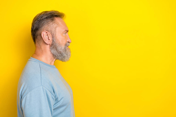Photo of cheerful handsome man pensioner dressed blue pullover looking empty space isolated yellow color background. - 写真・画像