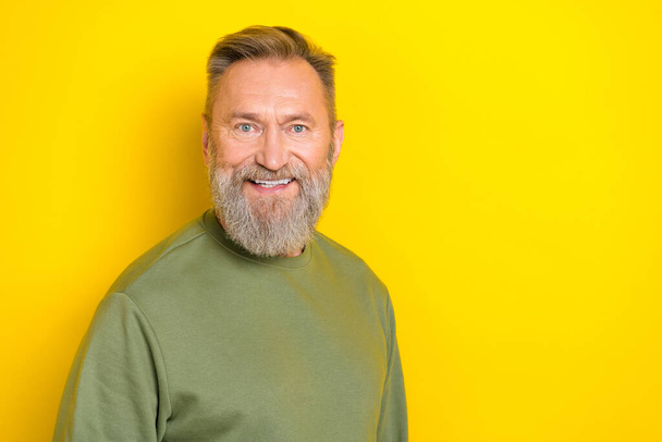 Photo of charming cheerful retired guy wear green sweater smiling empty space isolated yellow color background. - Фото, зображення