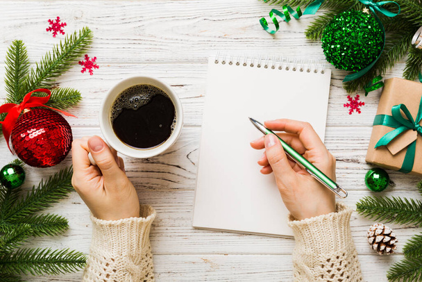 Woman writing Christmas to do list on notebook on colored background with xmas decorations. - Фото, зображення